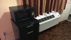 A black refrigerator, a white air conditioner, and a microwave on top of the refrigerator. - Satellite Motel (Los Angeles)
