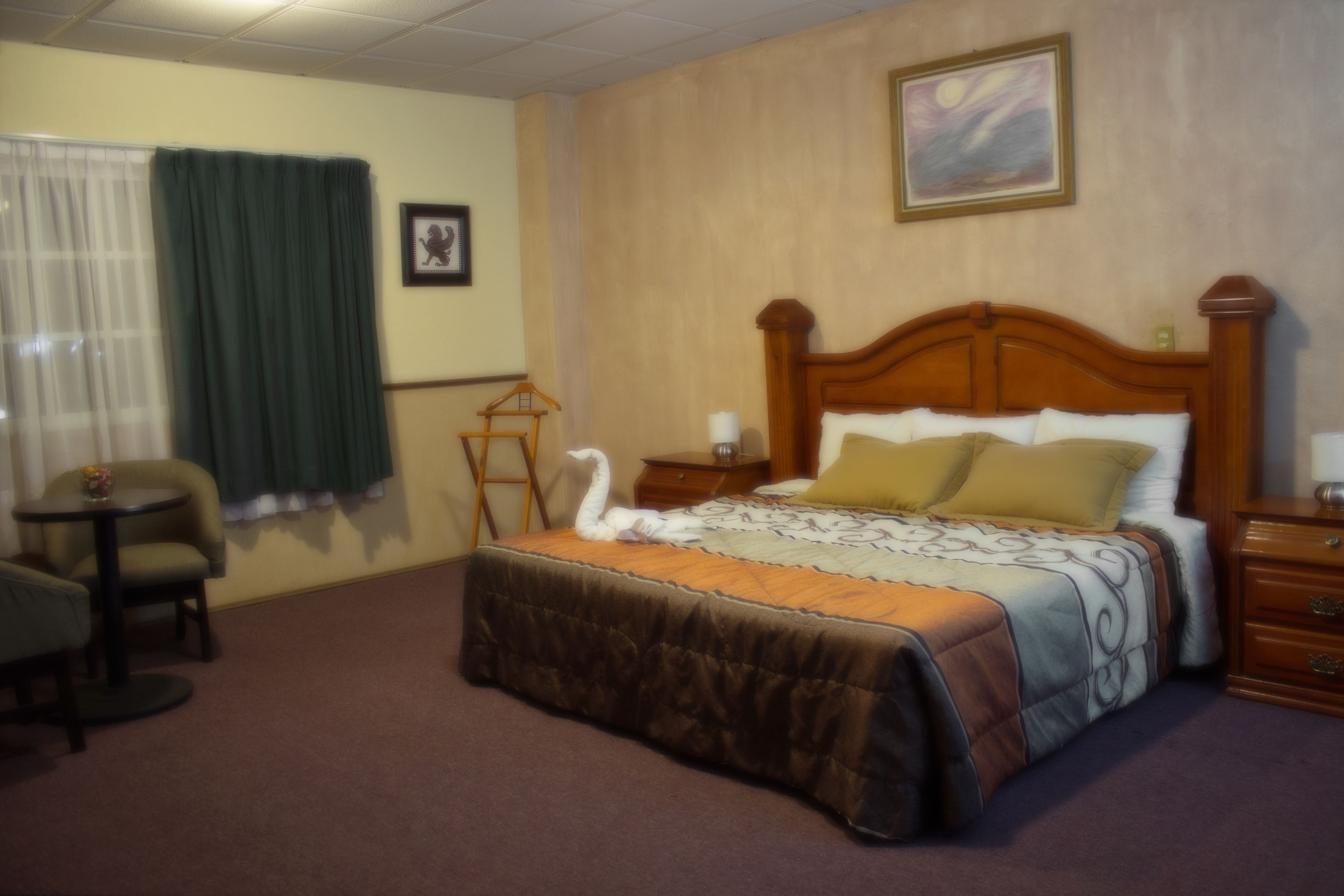 A hotel room with a bed, a chair, a small table, and a nightstand.