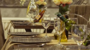 Una mesa de comedor lista con platos, cubiertos, copas de vino y centros de mesa florales.