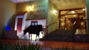 Un edificio con un letrero que dice "LA MANSION SUIZA" y una escalera que conduce a la entrada.