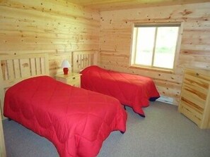 A cabin-style room with two beds, a window, and a wooden interior. - The Red Door Resort (Aitkin)