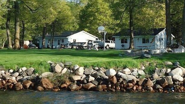 Une propriété située au bord d’un lac, comprenant une zone herbeuse, un quai et plusieurs maisons.