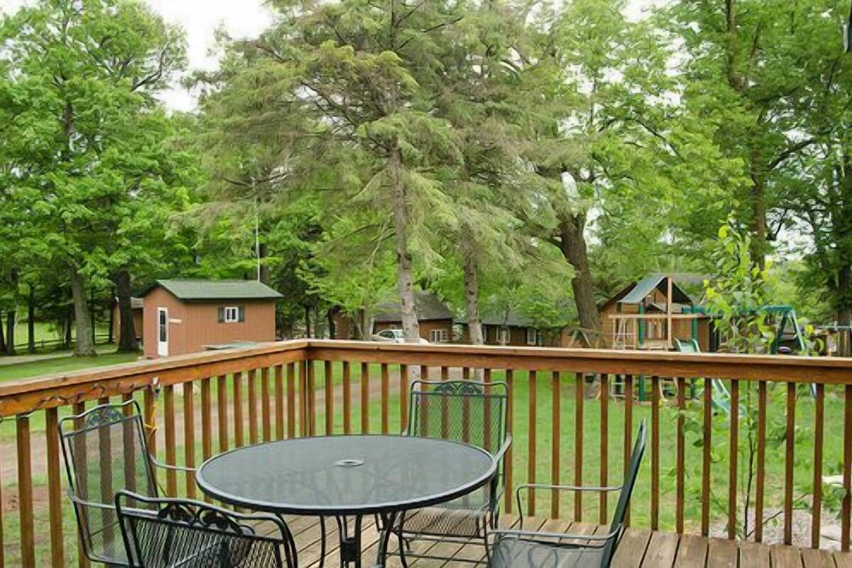 A wooden deck with a round table and chairs, surrounded by a wooden railing.