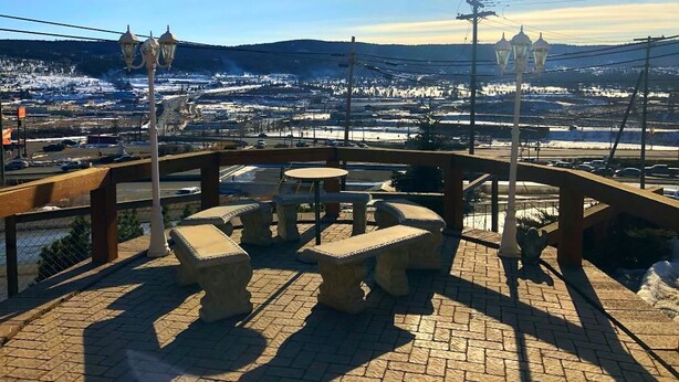 A terrace with stone furniture and a view of a snowy landscape. - Stampeder Motel (Williams Lake)