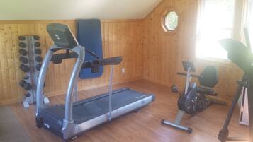 Un gimnasio en casa con cinta de correr, elíptica y pesas sueltas.