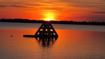 A sunset over a calm lake with a buoy in the foreground.