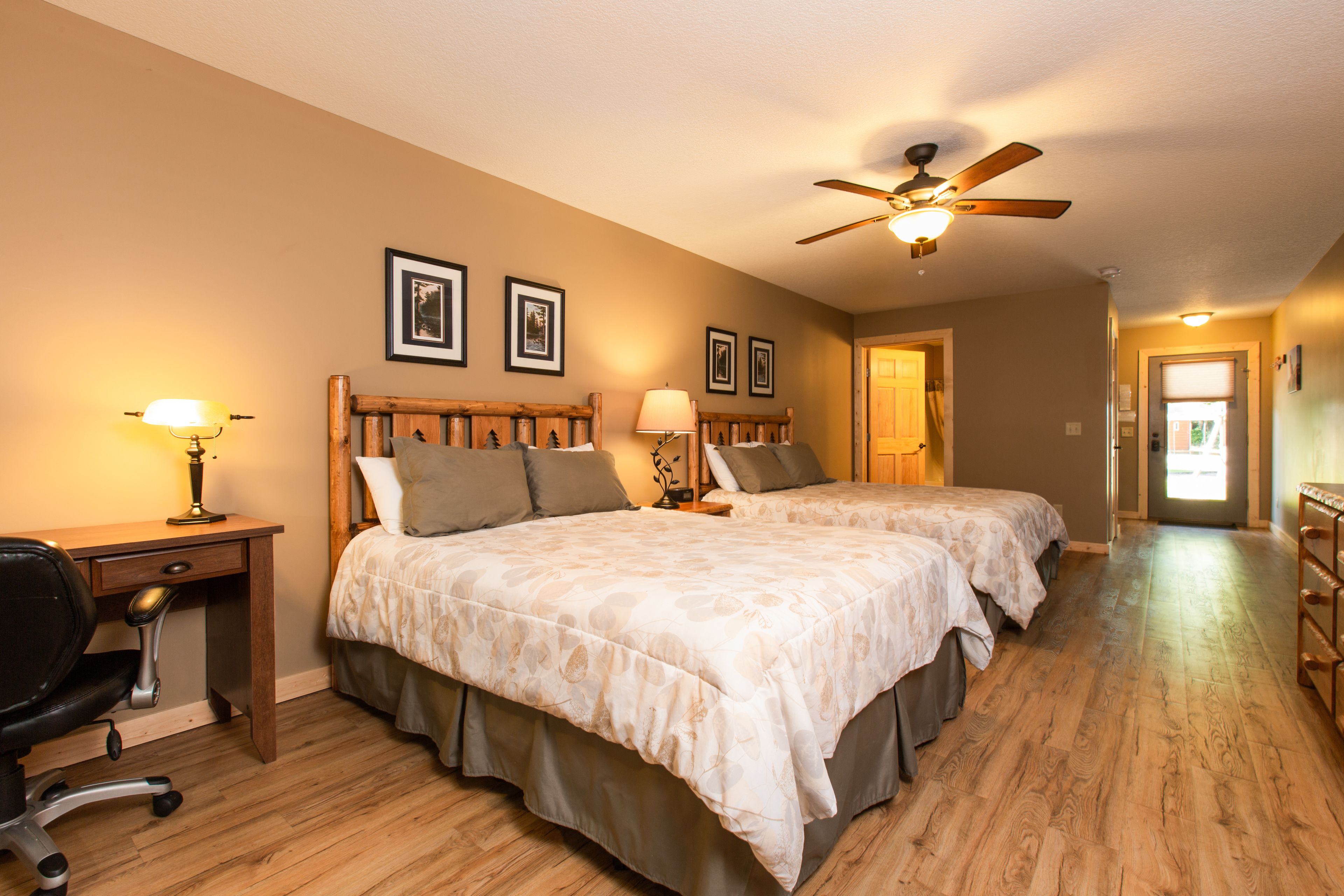 A bedroom with two beds, a desk, and a chair.