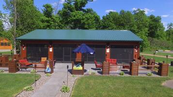 A covered outdoor seating area with wooden furniture and a blue umbrella.