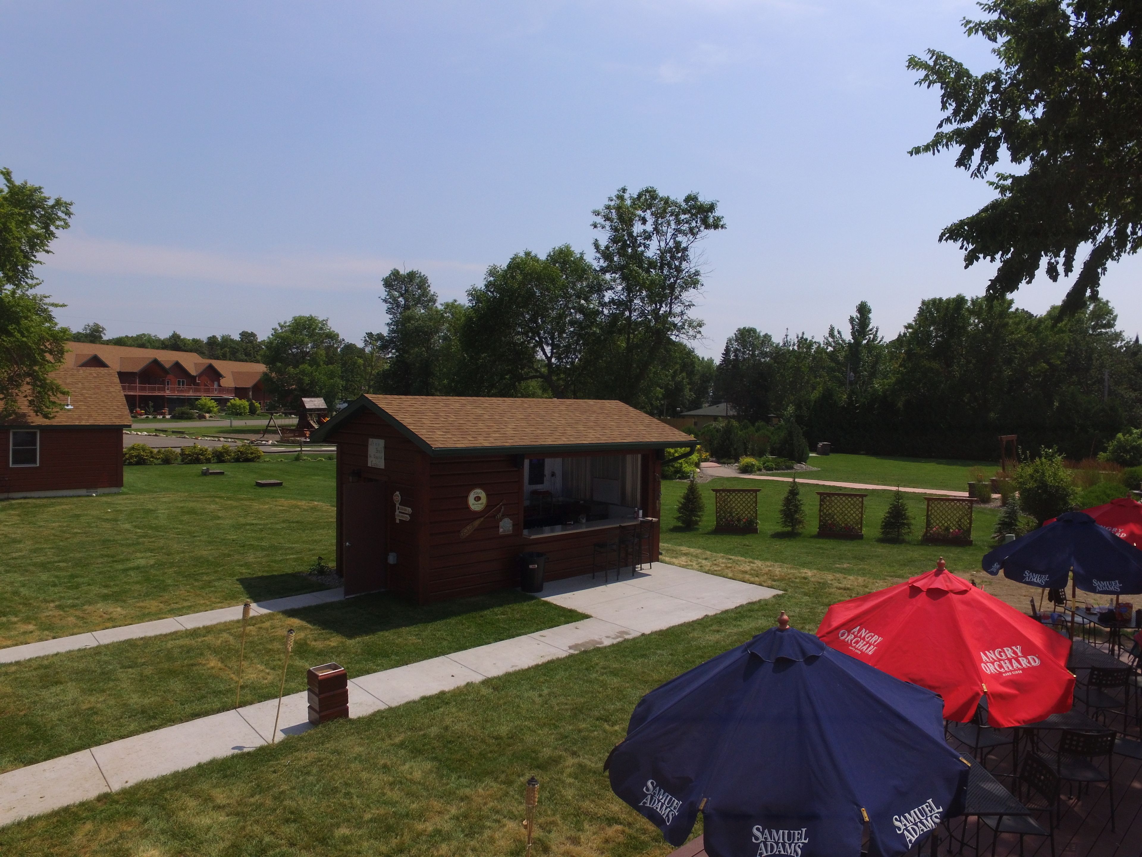 A small wooden structure with a porch, surrounded by a well-maintained lawn and trees.