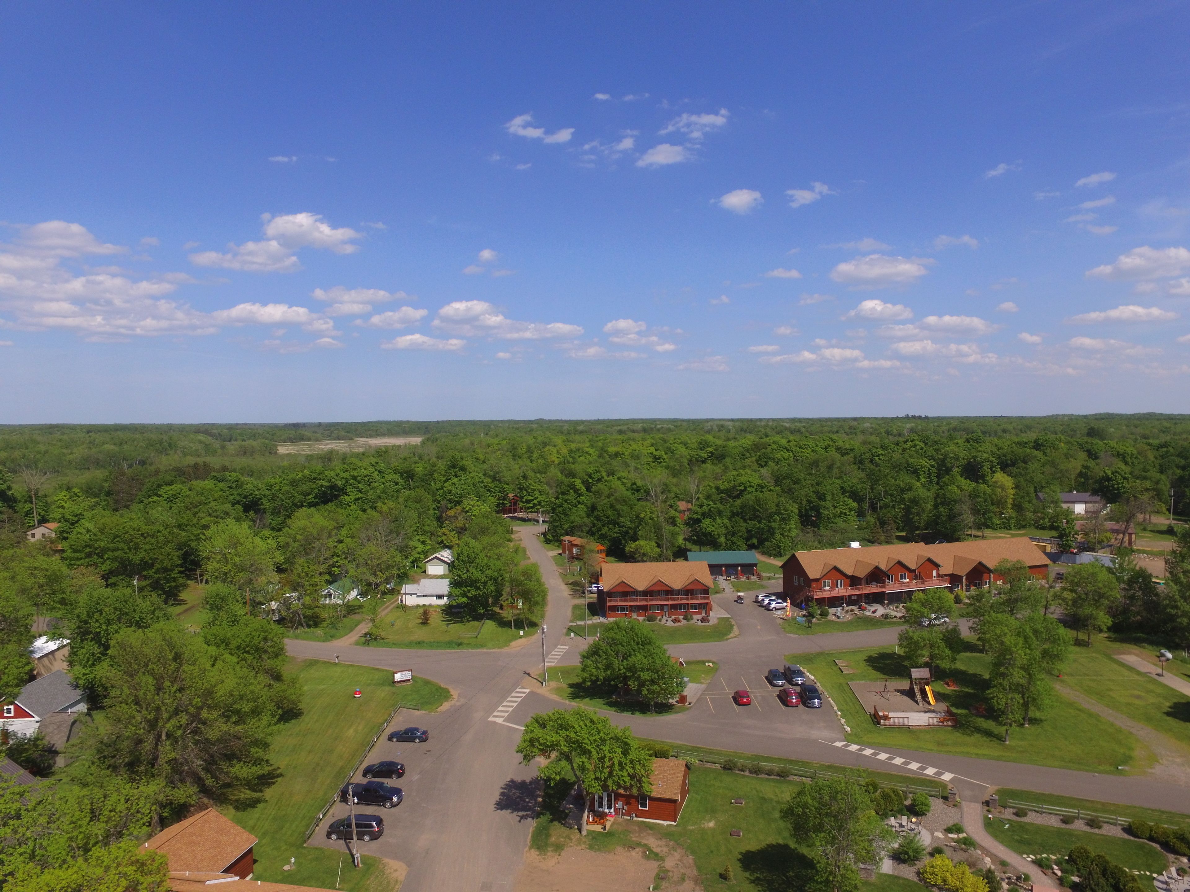 An aerial view of a resort with multiple buildings, a parking area, and surrounding greenery.