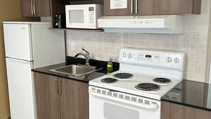 A kitchen with a white refrigerator, microwave, and stove. - Travelodge by Wyndham Valleyview AB (Valleyview)