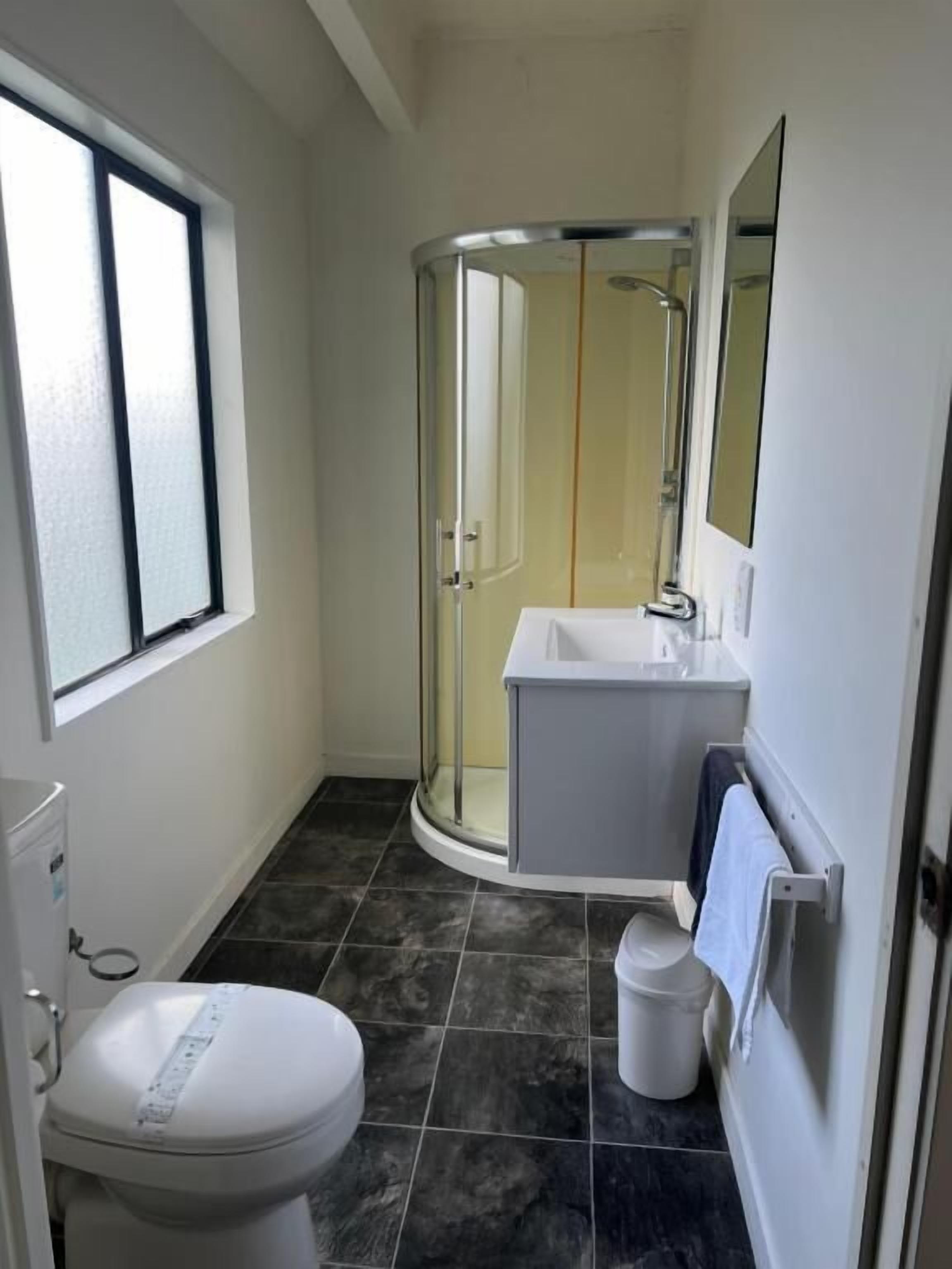 A bathroom with a toilet, a shower enclosure, and a sink.