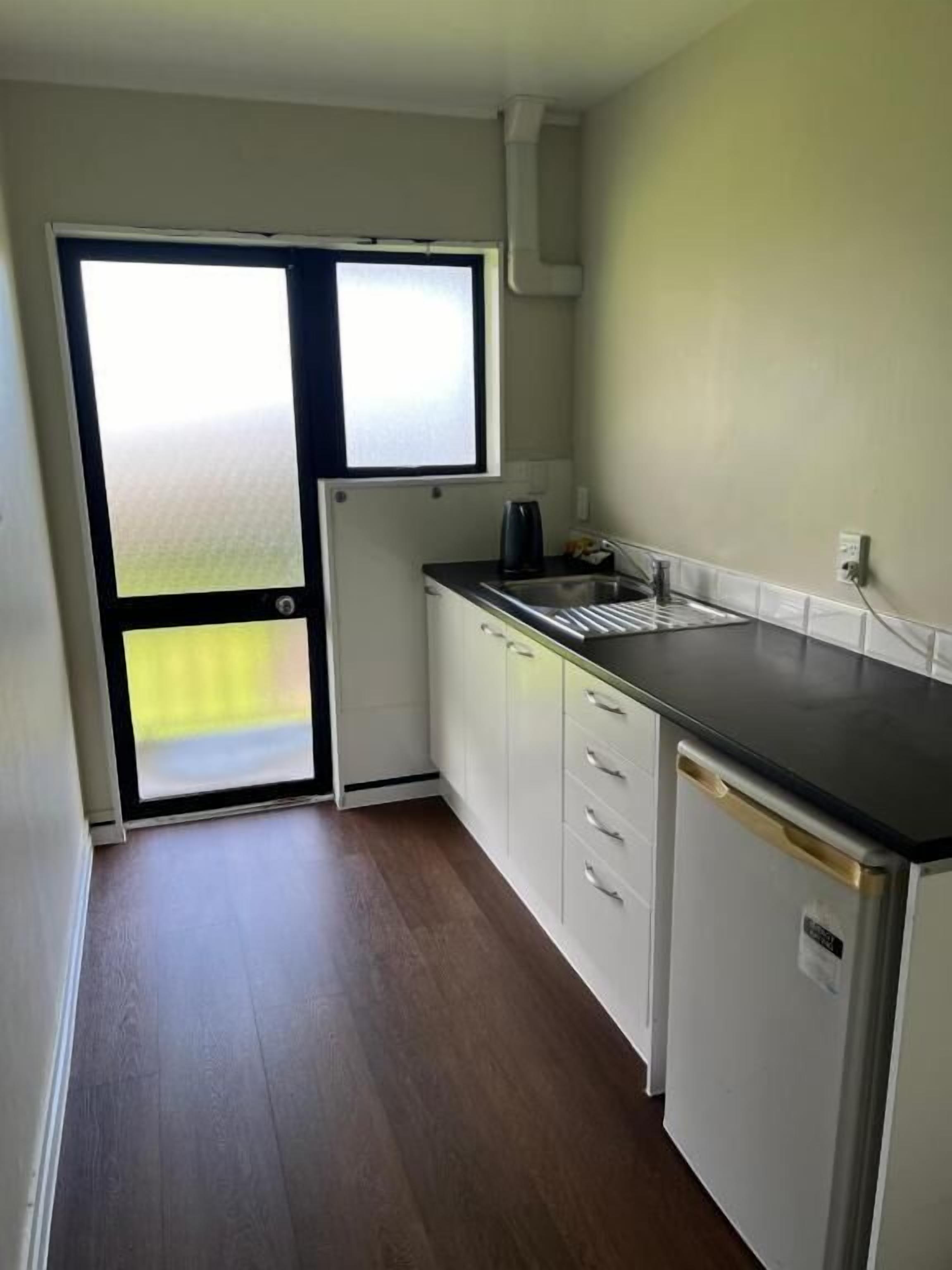A compact kitchen with a refrigerator, sink, and cabinets.