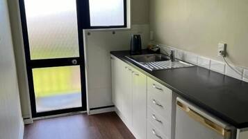 A compact kitchen with a refrigerator, sink, and cabinets.