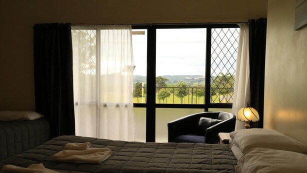 Une chambre d’hôtel avec un grand lit, une chaise et une vue sur la campagne par la fenêtre.