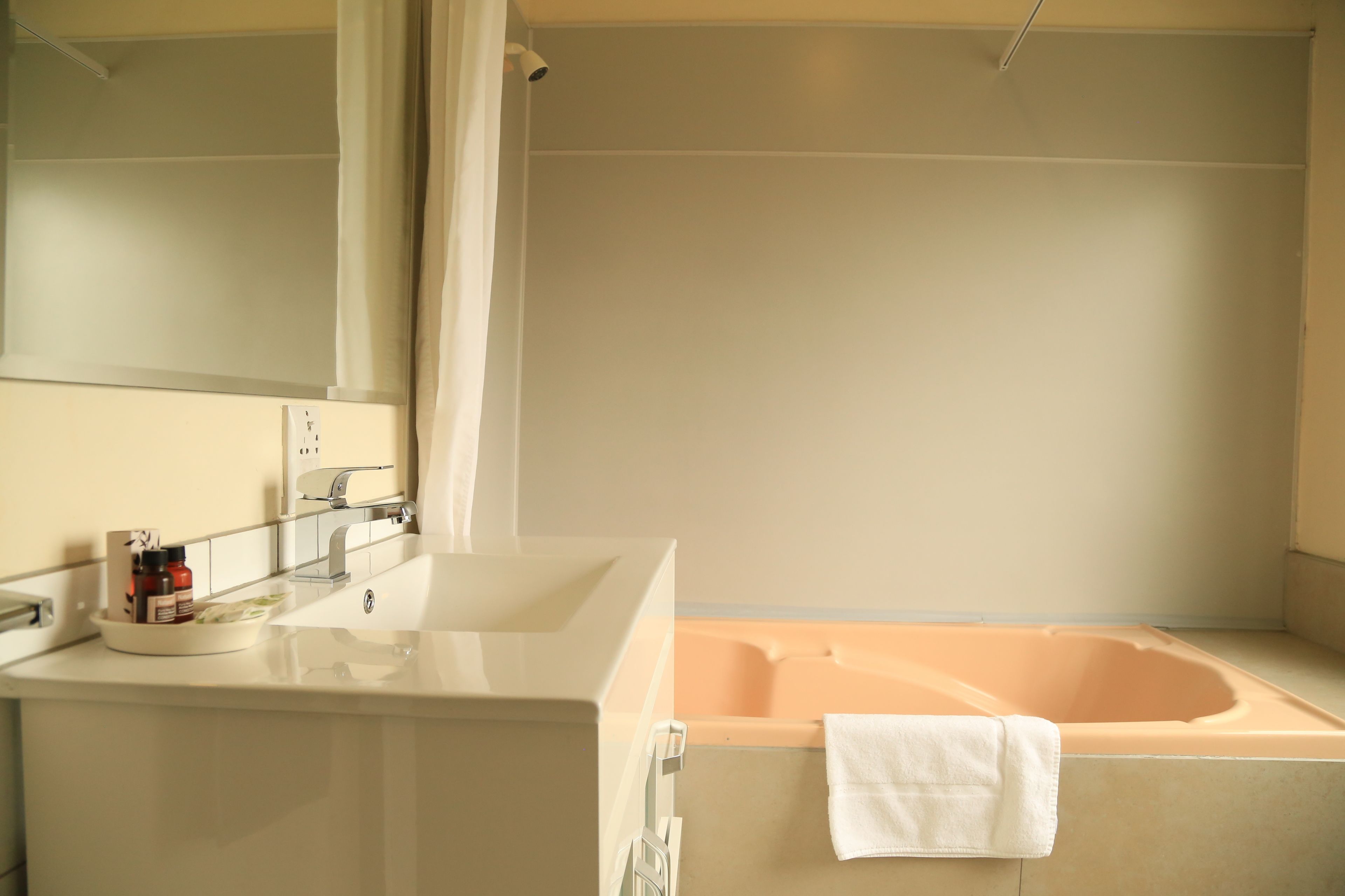 Un baño moderno con una bañera grande, un lavabo con espejo y una toalla colgada en la pared.