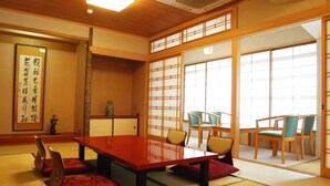 Ein traditioneller japanischer Raum mit Tatami-Bodenbelag, einem niedrigen Tisch und Stühlen.