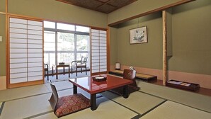 Ein traditioneller japanischer Raum mit Tatami-Boden, einem niedrigen Tisch mit roter Tischläufer und Schiebetüren.