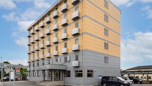A multi-story hotel with a yellow facade, numerous balconies, and a ground-level entrance. - Comfort Inn Kofu Showa Inter (Kofu)