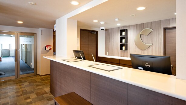 A reception desk with a computer, a bench, and a fire extinguisher. - Comfort Inn Kofu Showa Inter (Kofu)