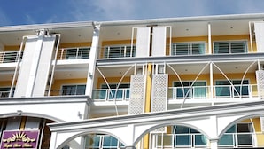 A multi-story hotel with balconies, arched windows, and a yellow facade. - Triple Three Patong (Patong)