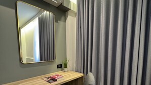 A room with a wooden desk, a chair, a mirror, and grey curtains. - iCheck inn Sukhumvit 19 (Bangkok)