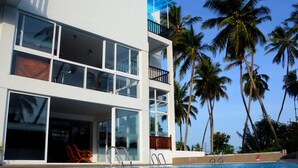 A modern hotel with a pool, large windows, and palm trees. - Sole Luna Resort & Spa (Tangalle)