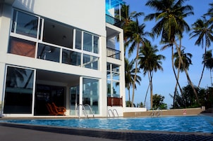 Um hotel moderno com piscina, janelas amplas e palmeiras.