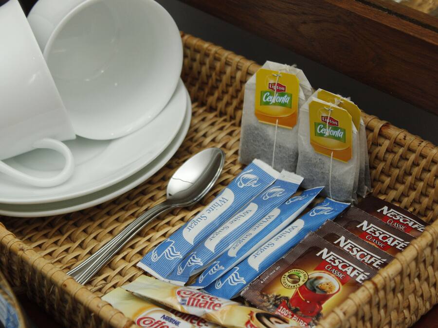 A wicker basket containing various coffee and tea products, including Nescafé Classic and Nestea, along with a spoon and white cups.