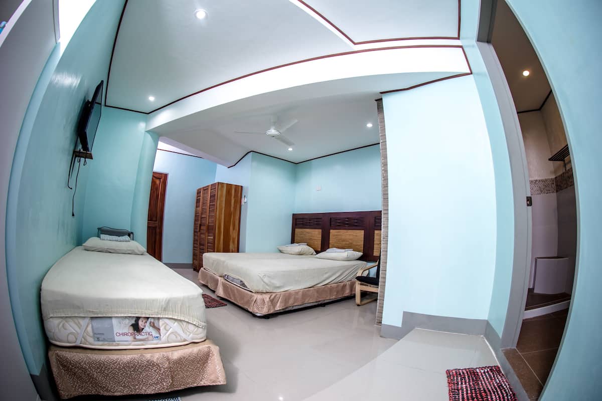 A hotel room with two beds, a ceiling fan, and a TV mounted on the wall.