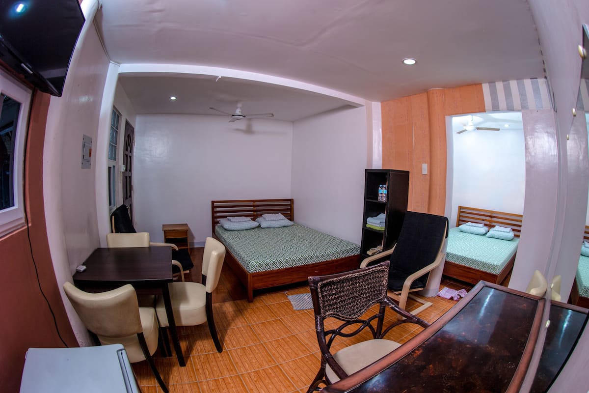 A compact hotel room with a single bed, a small desk, a chair, a television, and a wardrobe.
