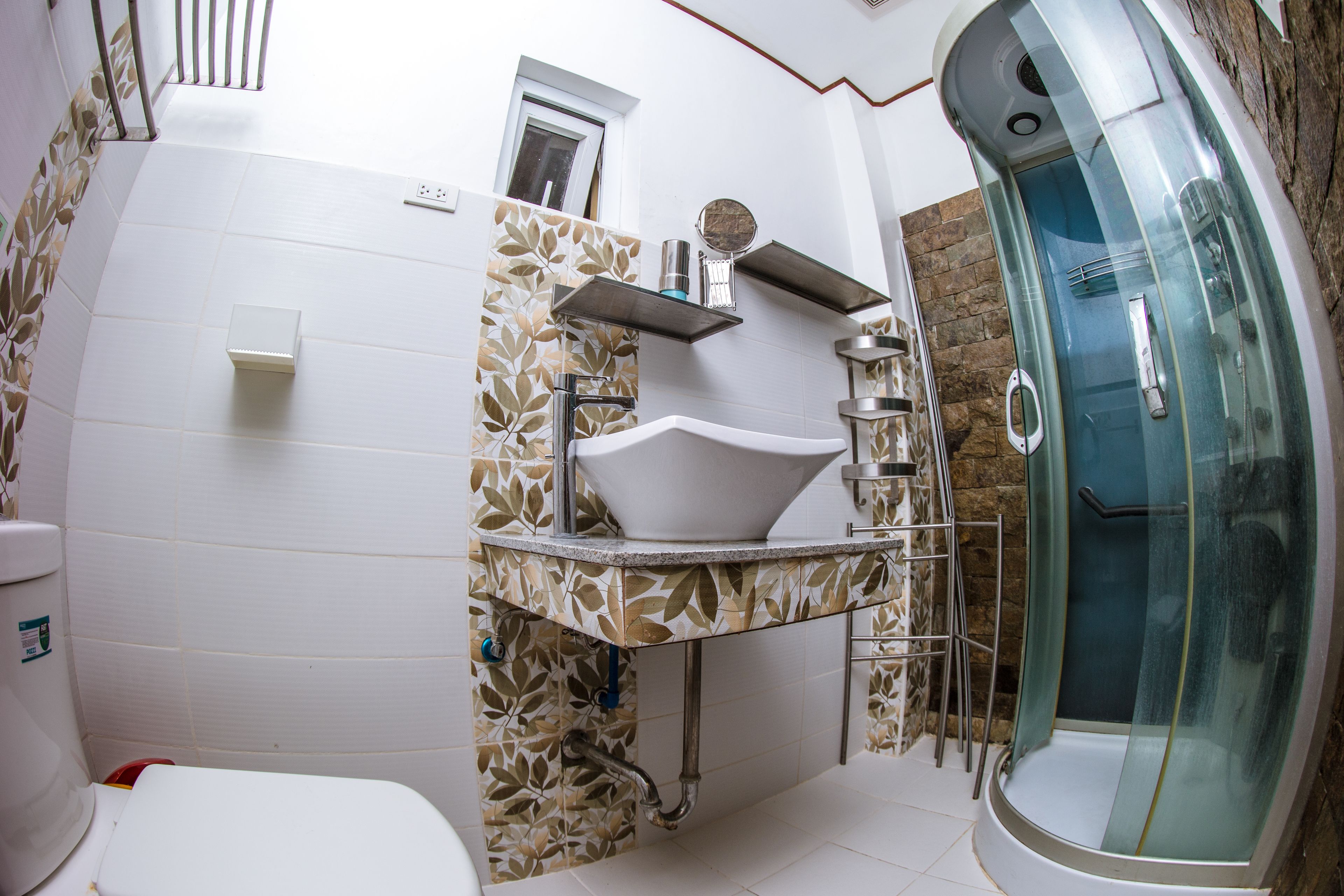 A modern bathroom with a white sink, a glass-enclosed shower, and a patterned tile backsplash.