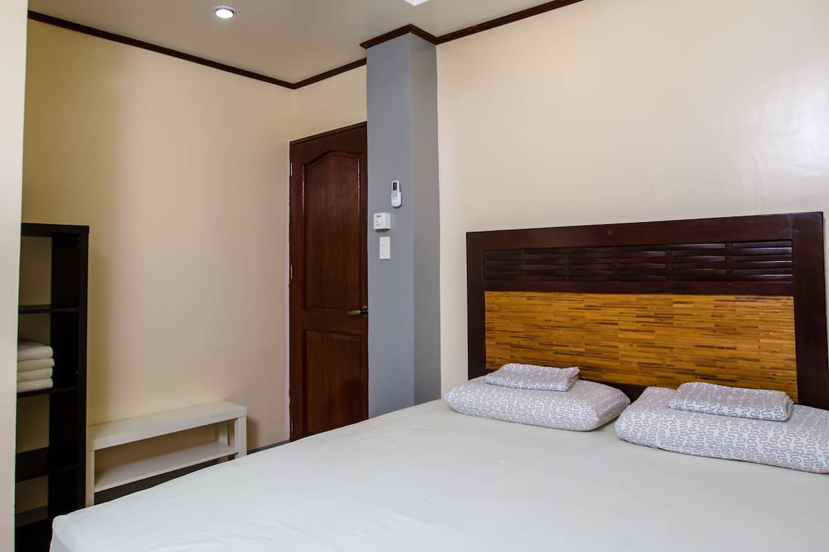 A bedroom with a bed, a ceiling fan, a wooden headboard, and a wardrobe.