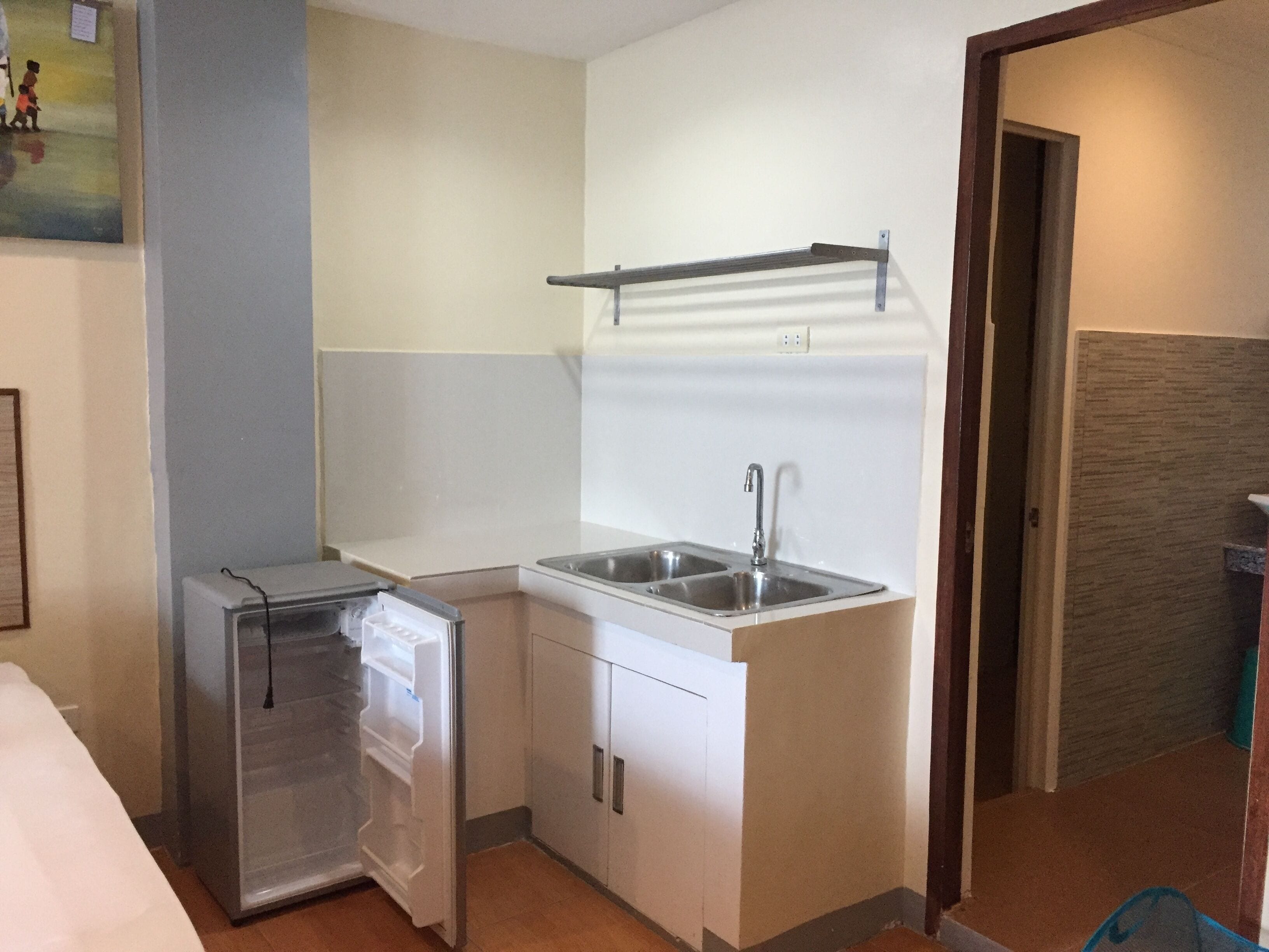 Una cocina compacta con refrigerador, lavamanos y una pequeña encimera.