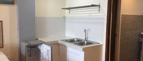 Una cocina compacta con refrigerador, lavamanos y una pequeña encimera.
