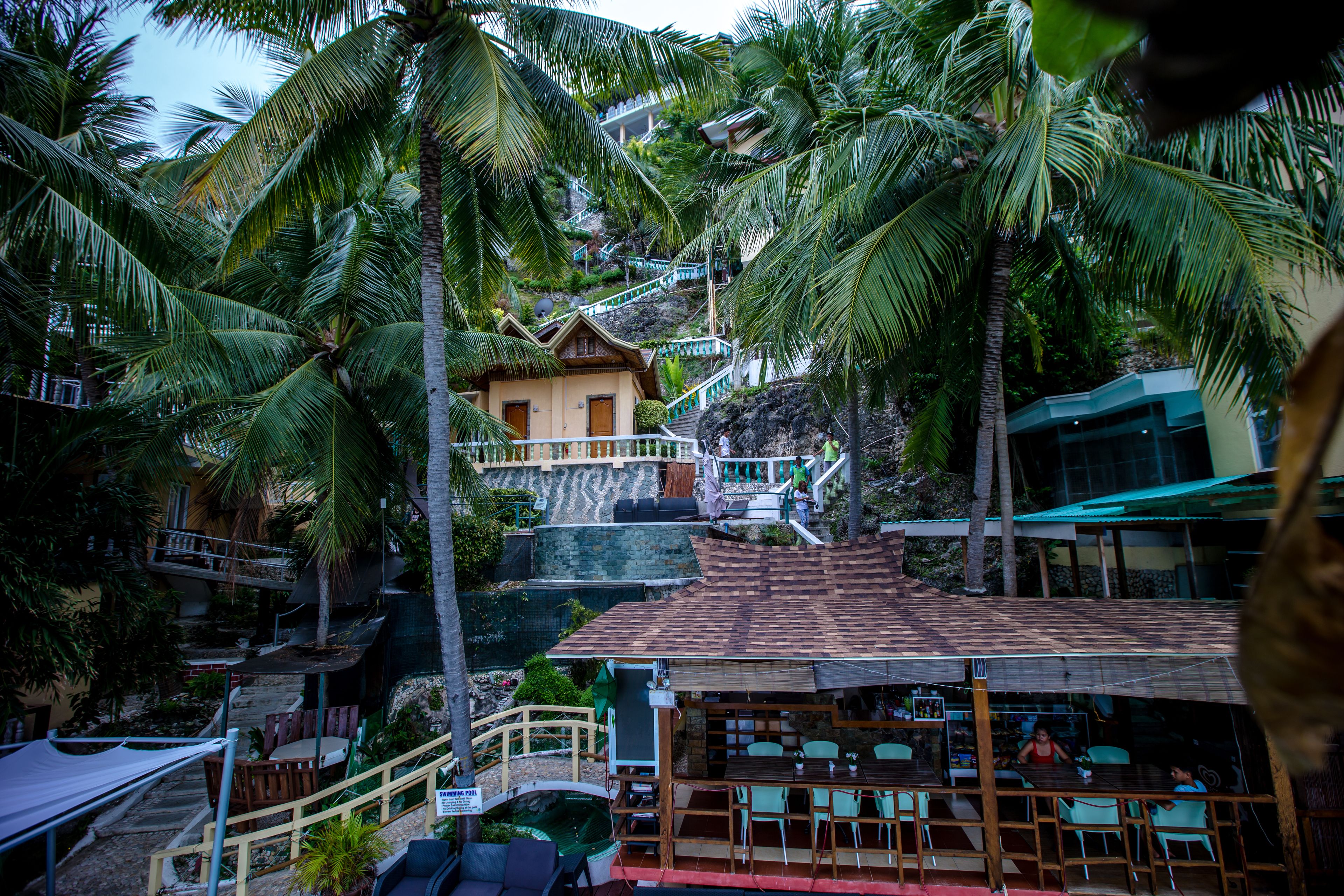 A resort with a restaurant area, outdoor seating, and a staircase leading to a building.