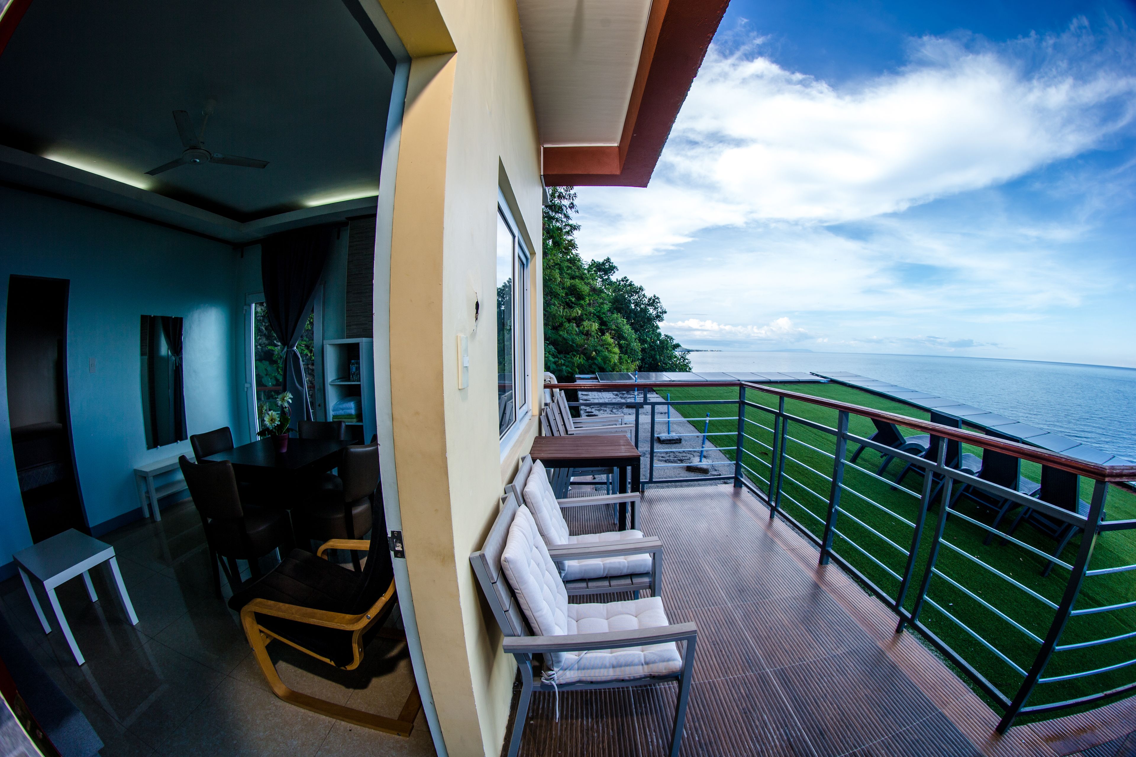 Ein Balkon mit Sitzgelegenheit, Blick aufs Meer und Essbereich mit Tischen und Stühlen.