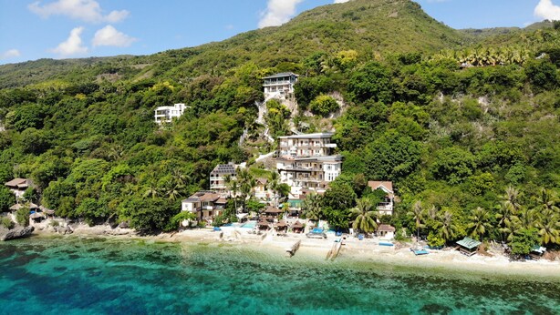 A coastal resort with multiple buildings, clear turquoise waters, and lush greenery. - Seafari Resort Oslob (Oslob)
