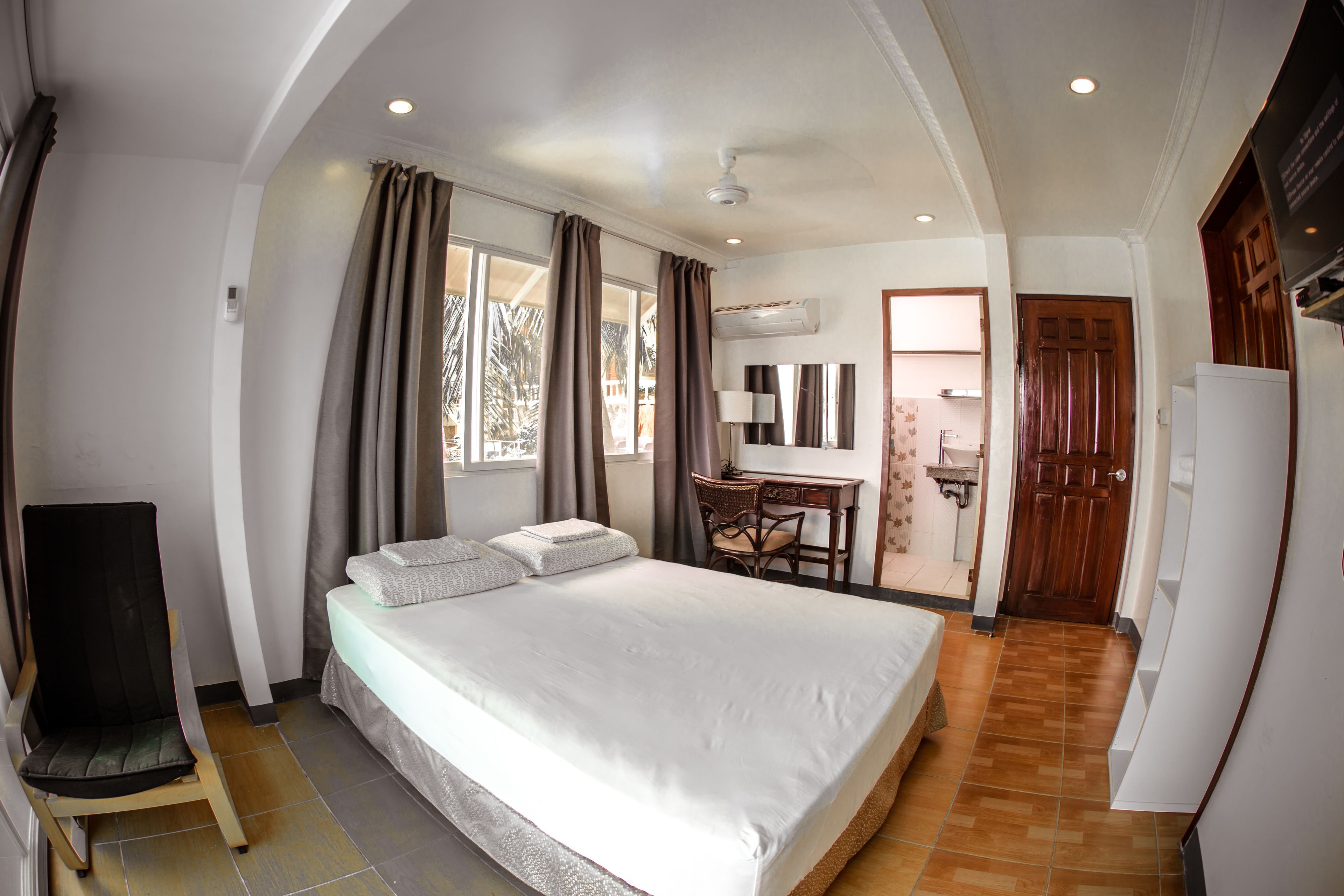 A bedroom with a large bed, a desk, and a chair.
