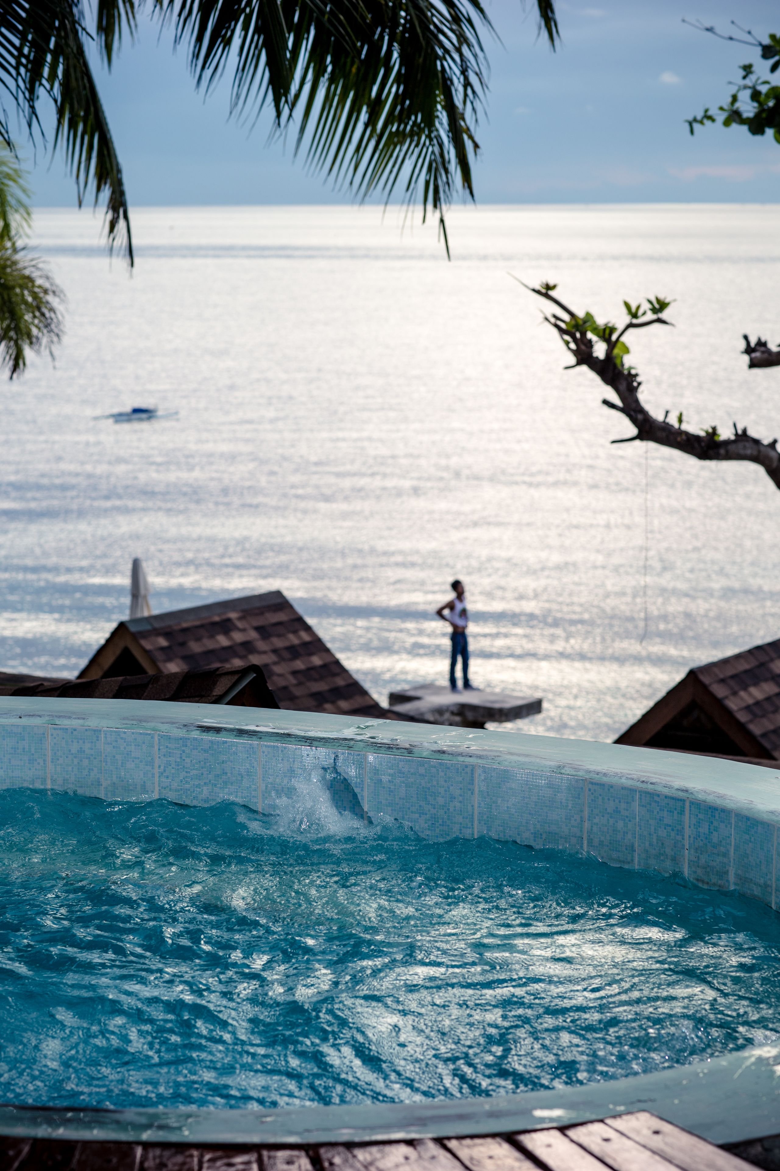 A swimming pool with a view of the sea and a person standing by the pool's edge.