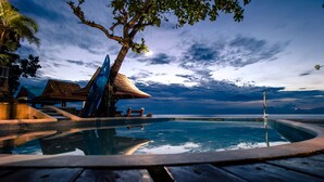 A pool area with a wooden deck, a thatched-roof structure, and a view of the ocean. - Seafari Resort Oslob (Oslob)