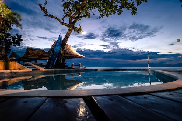 A pool area with a wooden deck, a thatched-roof structure, and a view of the ocean. - Seafari Resort Oslob (Oslob)