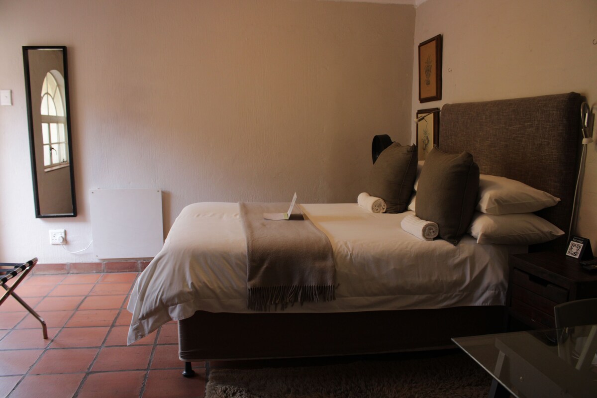 A bedroom with a bed, nightstand, and a mirror on the wall.