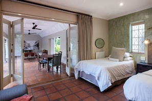 A hotel room with a bed, a dining area, and a view through an open door.