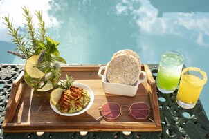 Una bandeja con comida y bebidas en una mesa junto a una piscina.