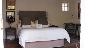 A neatly made bed with a sign indicating a free Wi-Fi zone, a bedside table with a fan, and a small desk with a chair.