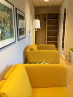 Una habitación con un sofá amarillo, una lámpara y un armario de madera.