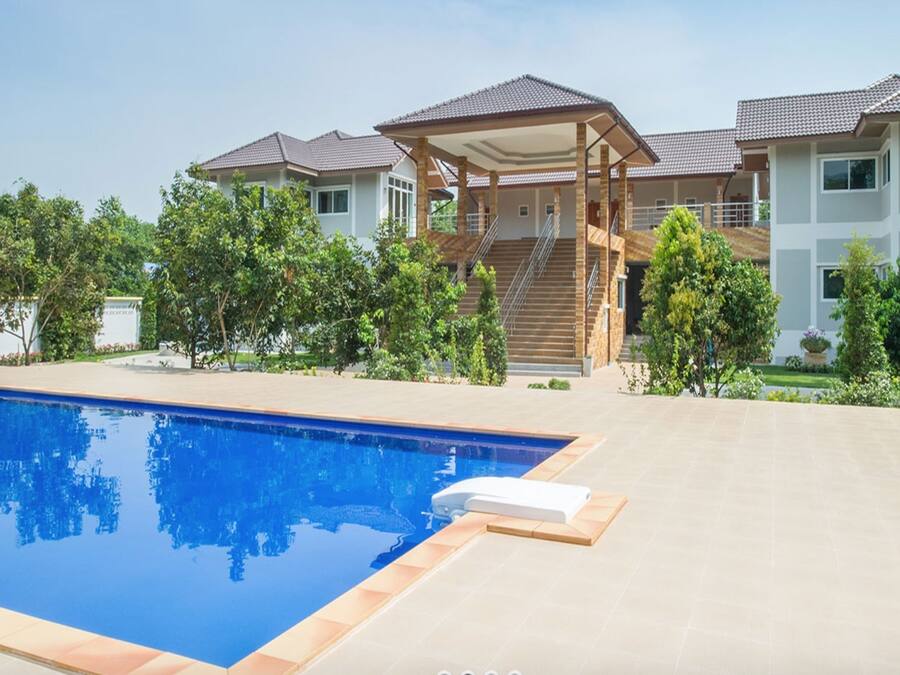 A modern house with a swimming pool, covered patio, and lush greenery.