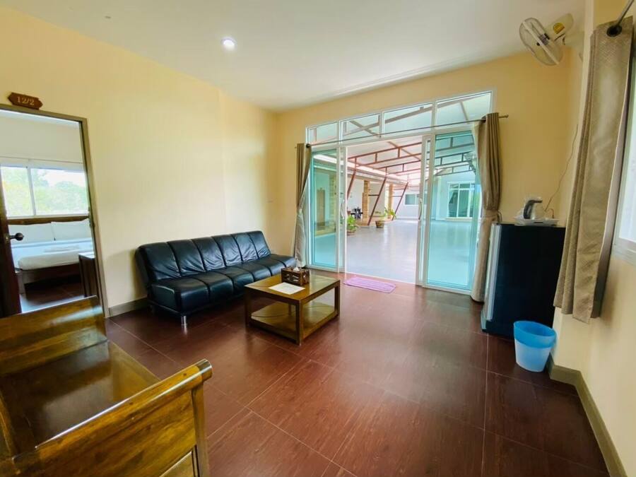 Una sala de estar con un sofá de cuero negro, una mesa de centro de madera y un ventanal que da a un balcón.