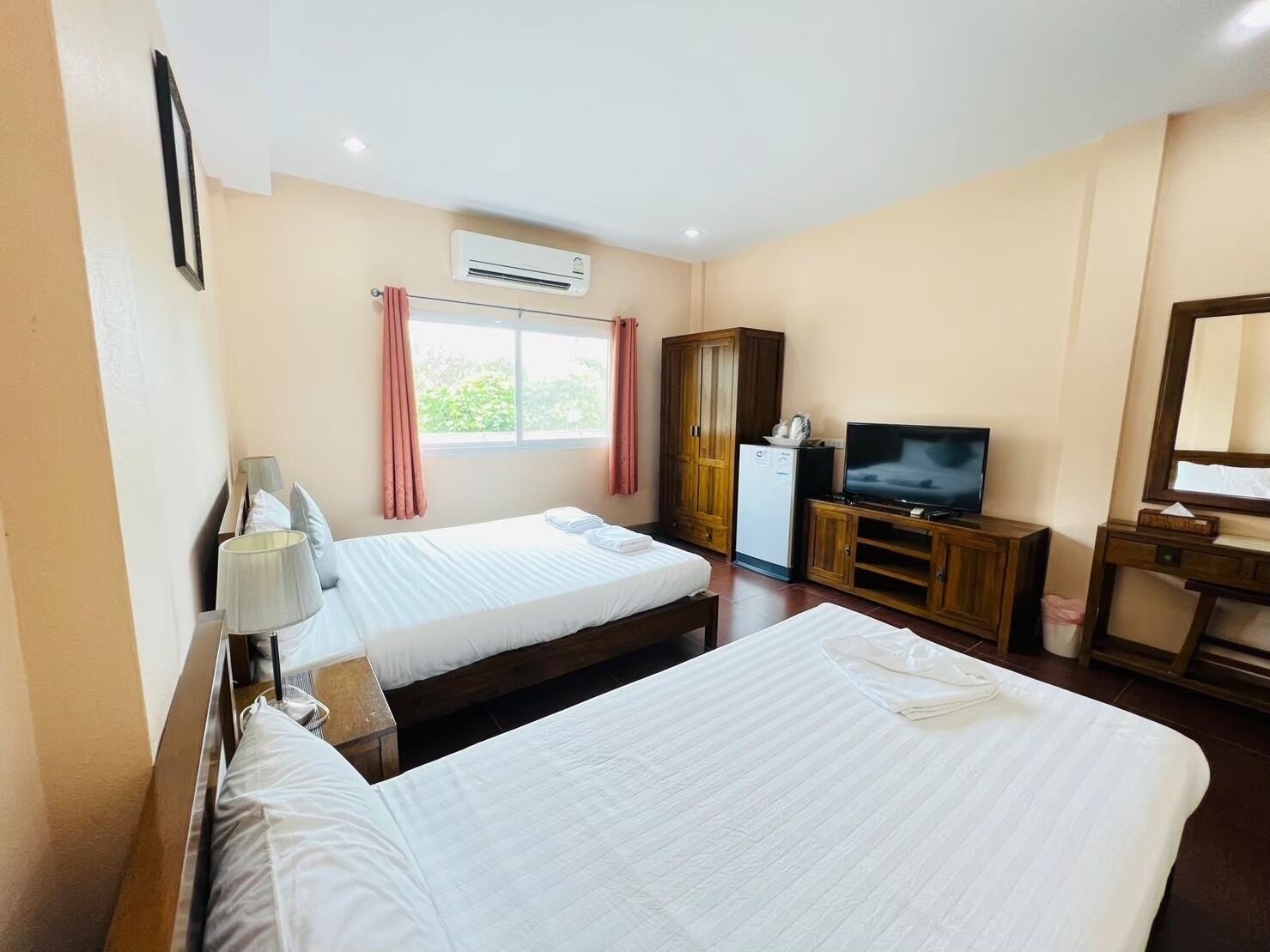Habitación de hotel con dos camas, un televisor, un armario y aire acondicionado.